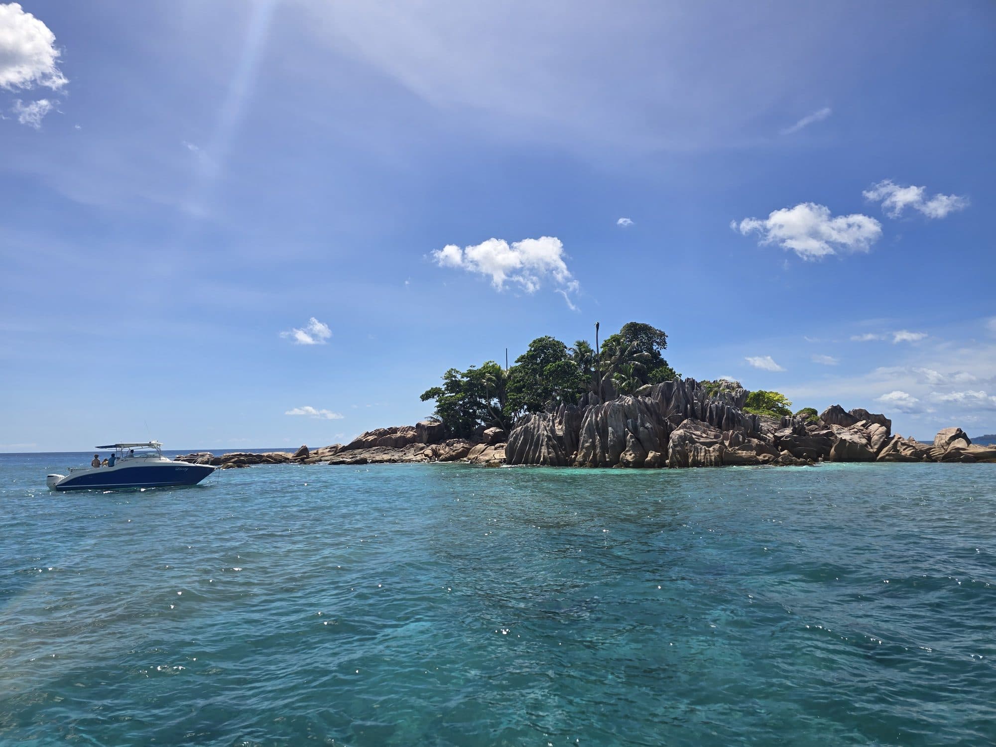 The granite islet of St. Pierre with a boat moored in turquoise water, Seychelles