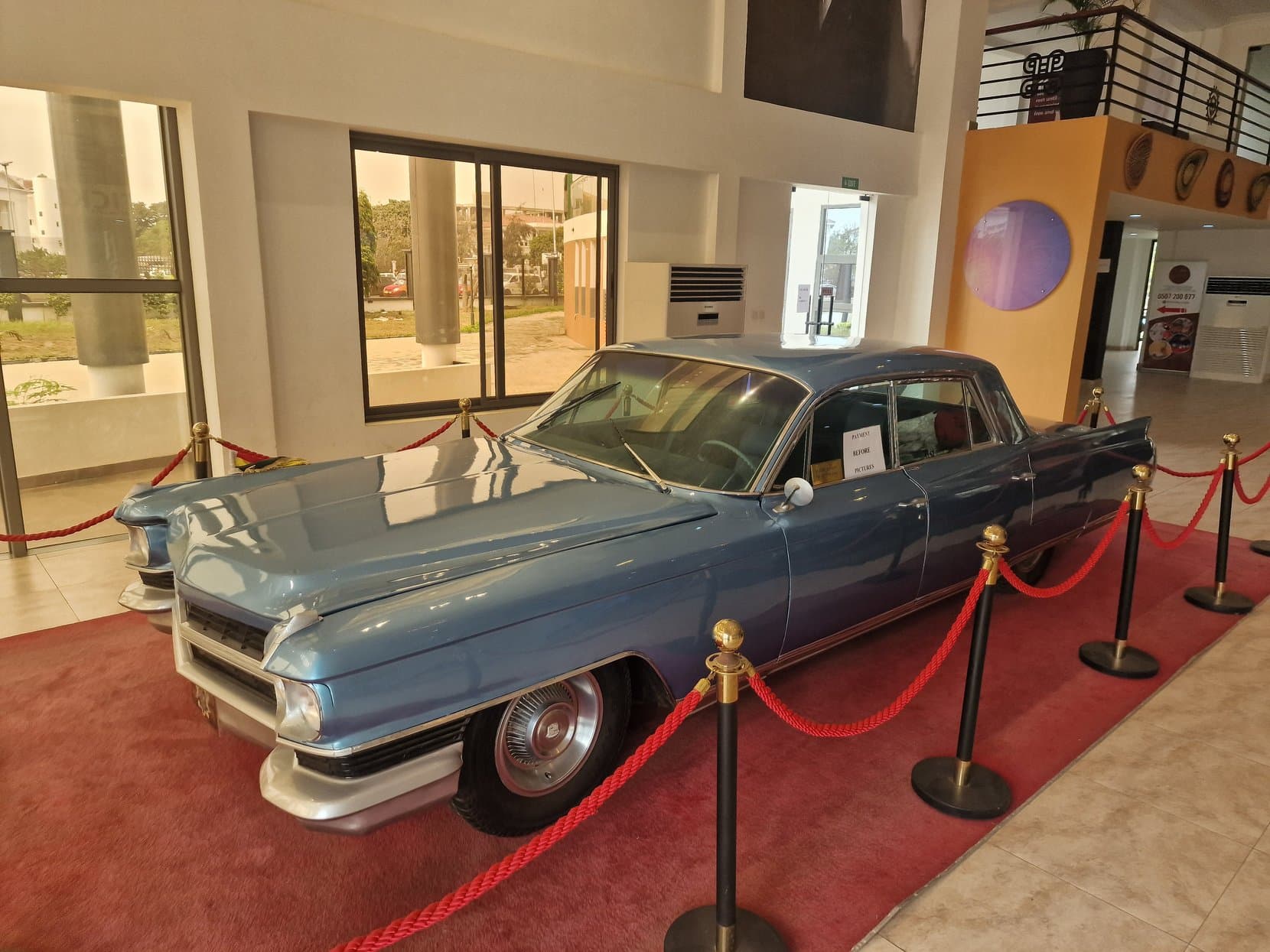 A preserved blue state car on a red carpet behind a rope inside a museum, Accra, Ghana