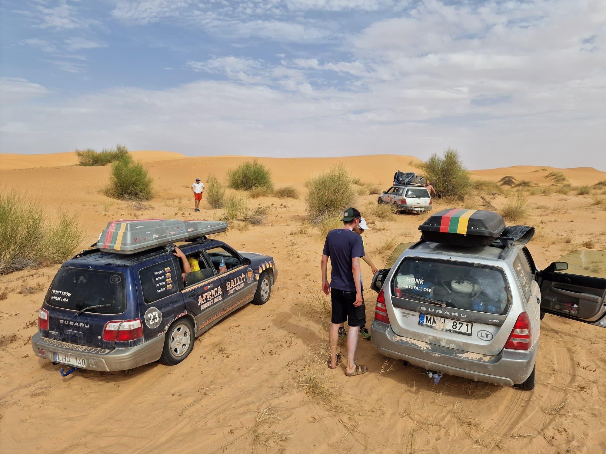 Two cars stopped in soft dune sand, one dug in to the axles