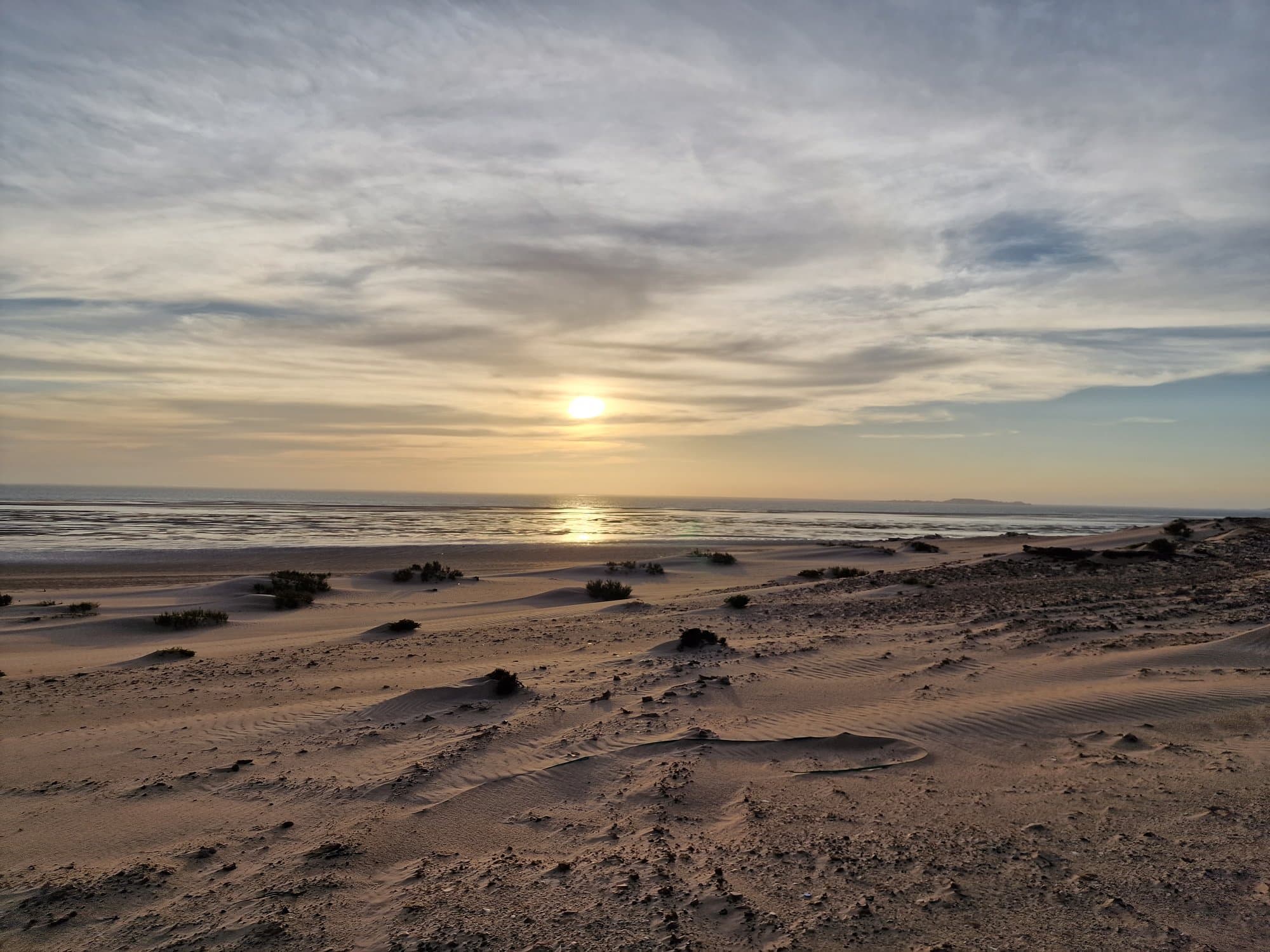 The sun setting over the Atlantic seen from dark dunes on the Western Sahara coast