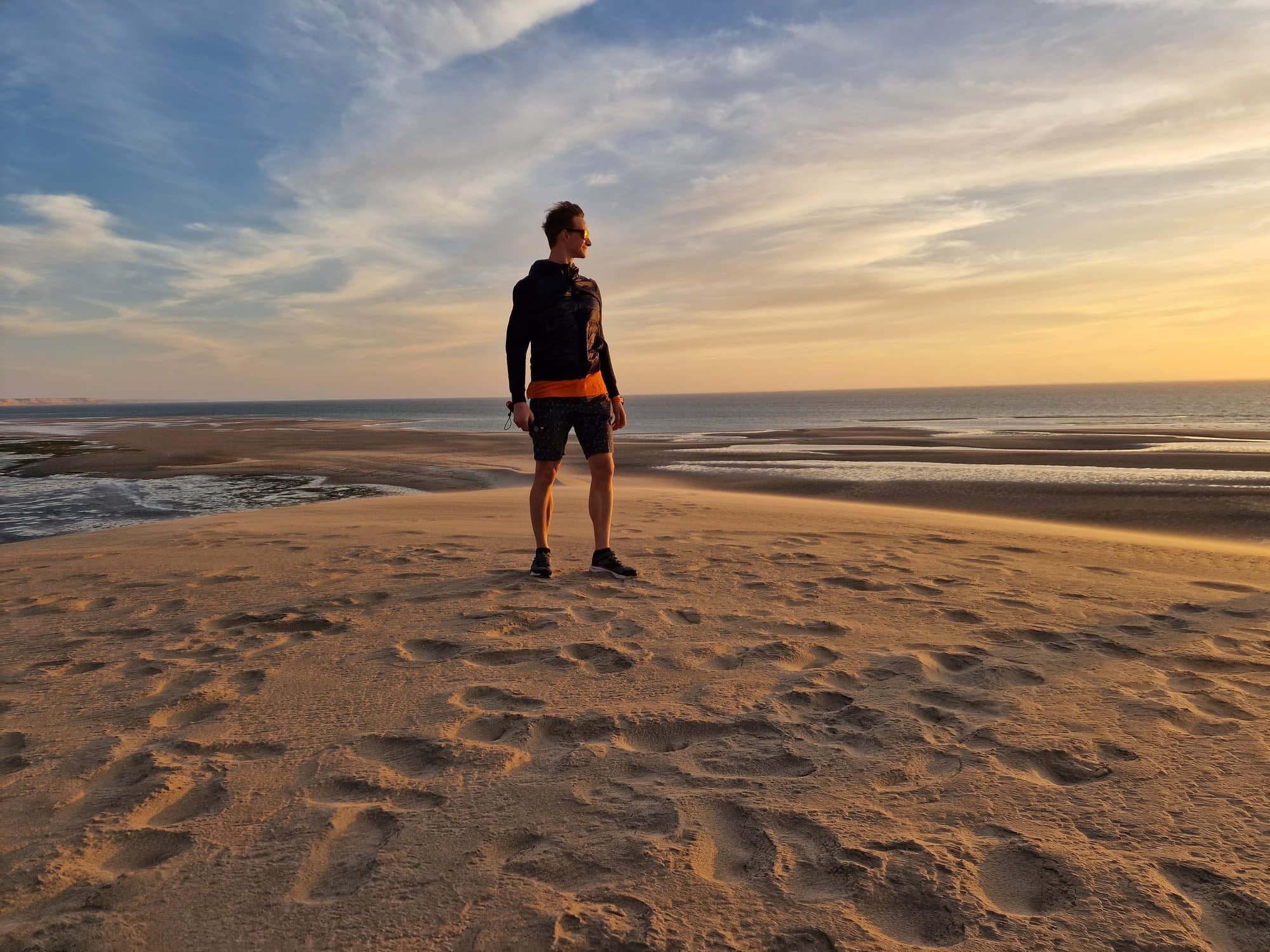 A lone figure on vast tidal sand flats at sunset