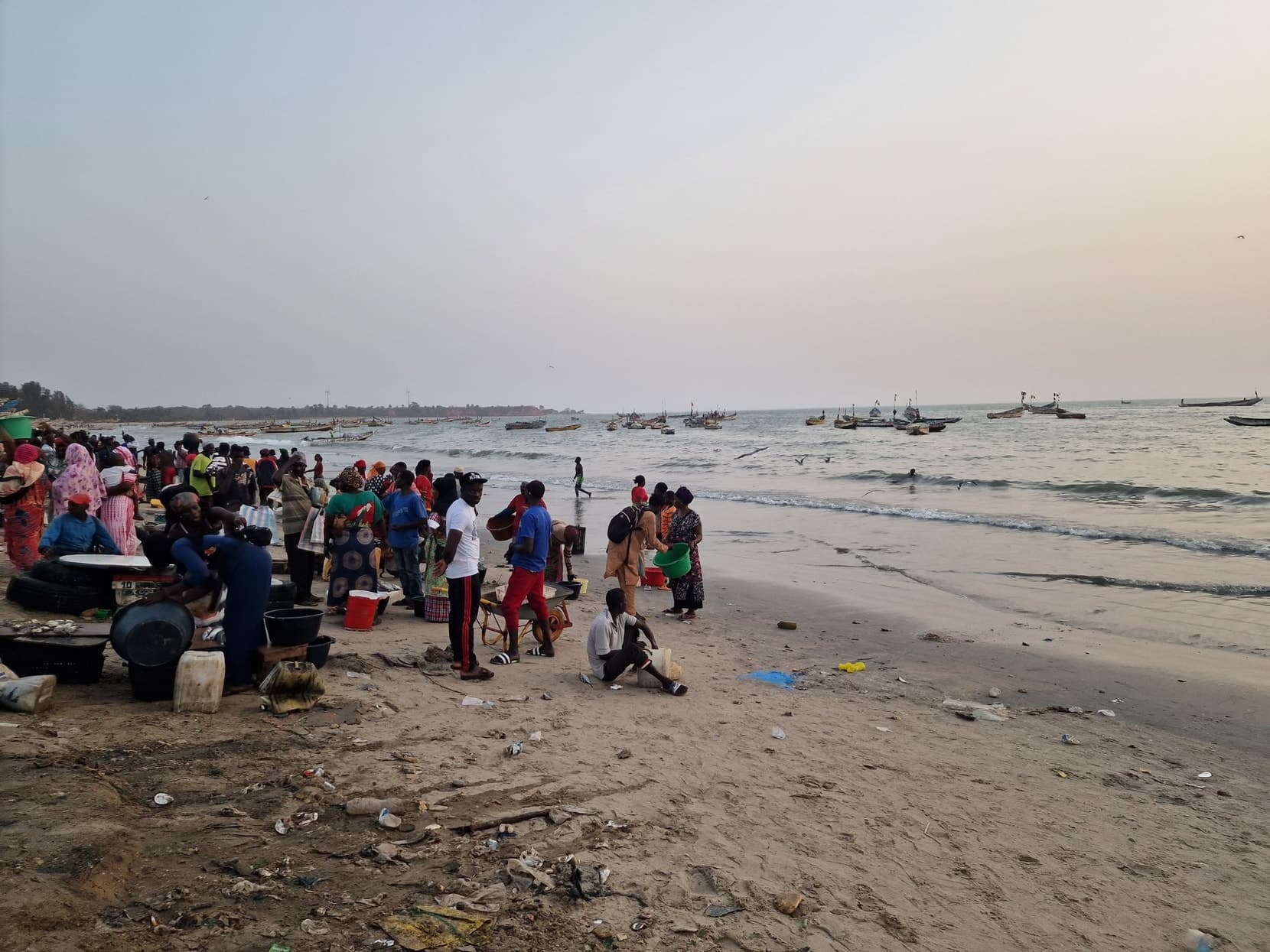 Crowds on the beach at Tanji fish market at sunset, pirogues offshore