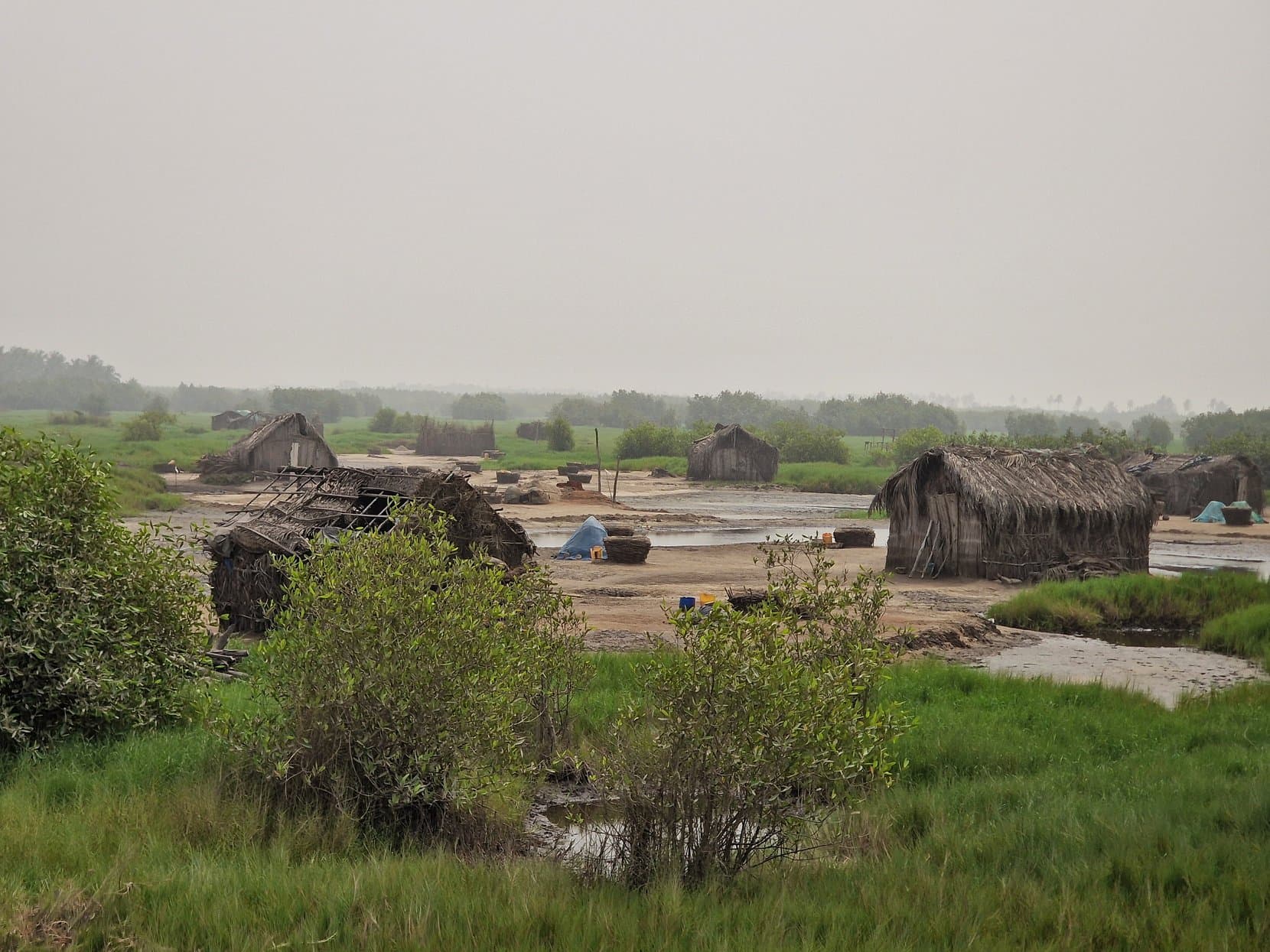 Thatched huts and moored boats on the marshy edge of a lagoon outside Ouidah, Benin