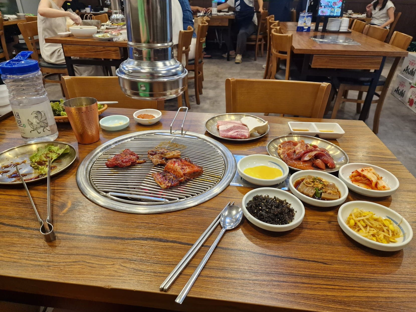 A Korean barbecue table with a round grill, tongs and side dishes, Myeongdong, Seoul