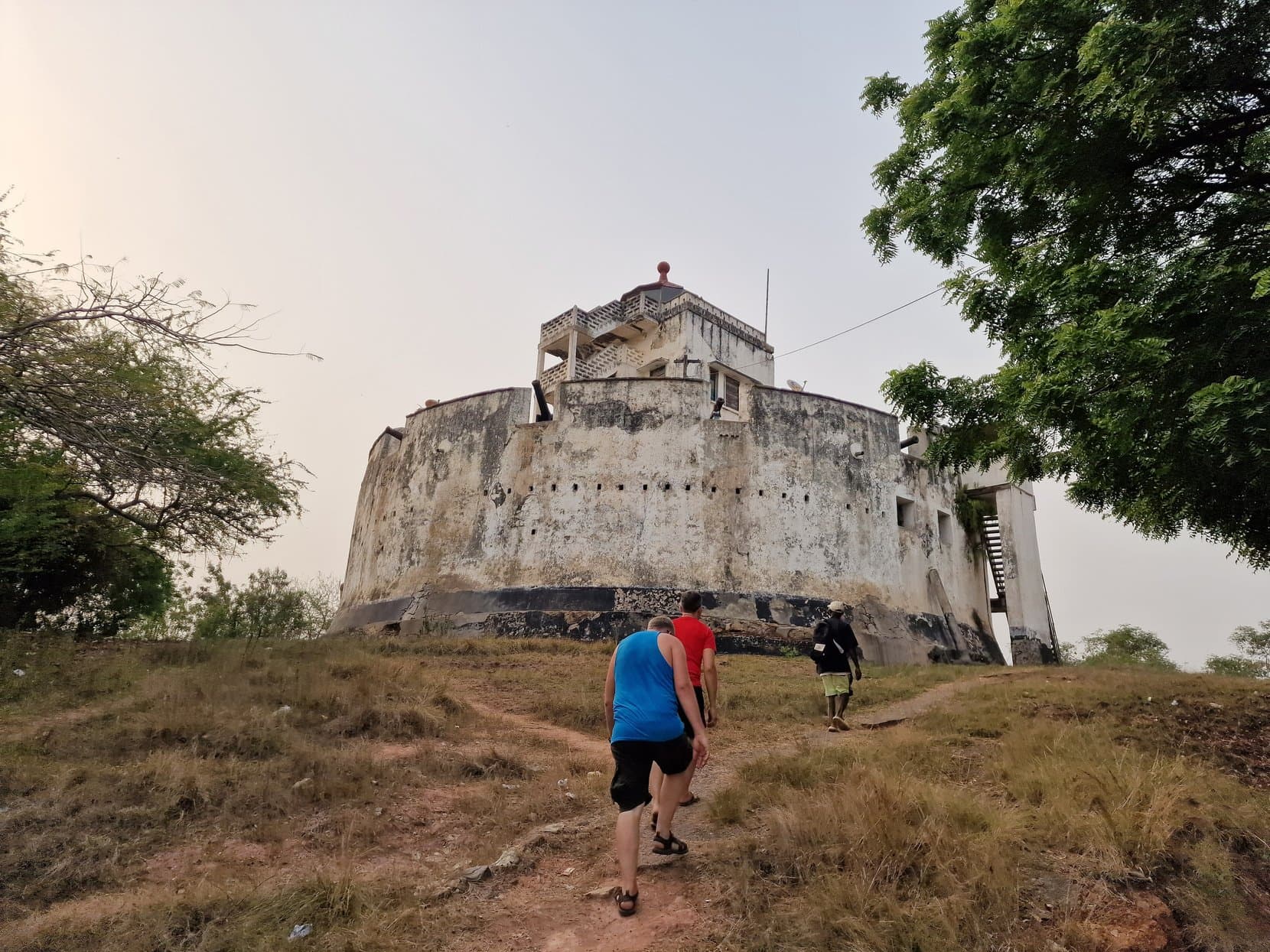 A small round hilltop fort on dry grass above Cape Coast town, Ghana