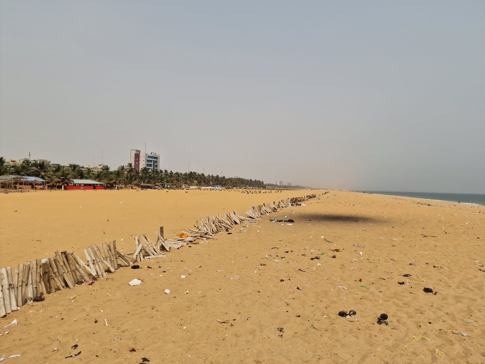 A long empty sandy beach with the city's towers at the far end, Lomé, Togo