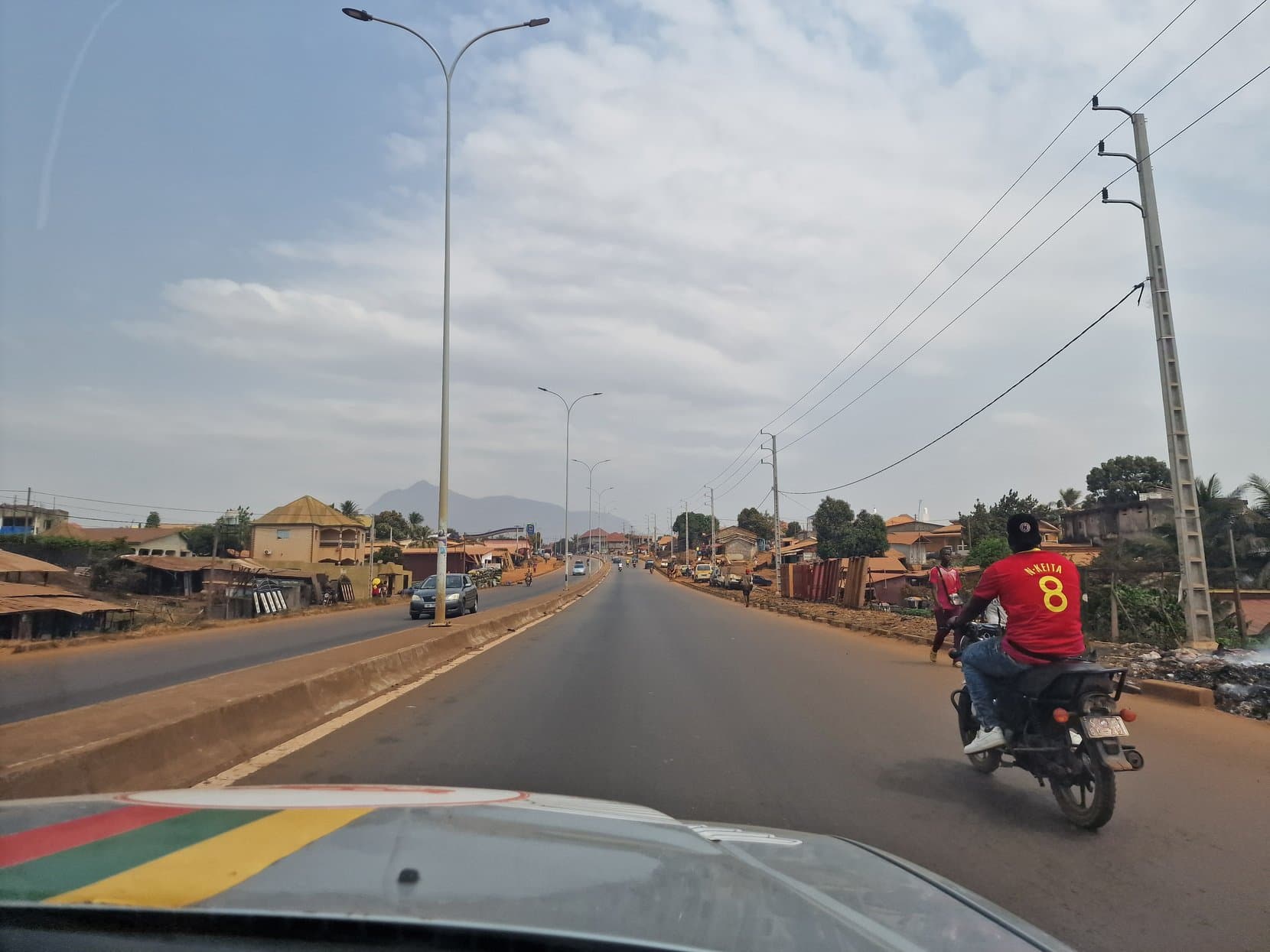 A motorbike rider in a Guinea football shirt on the divided highway out of Conakry
