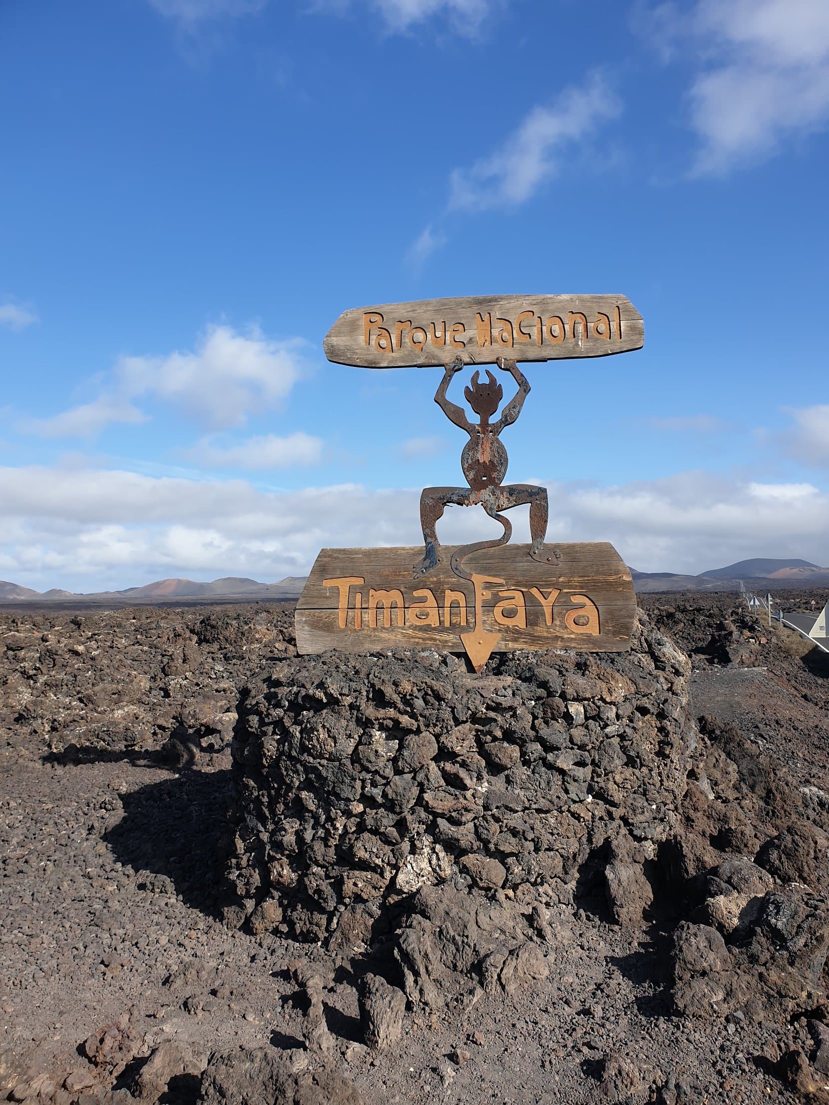 The Timanfaya national park sign with its fire-devil emblem on a lava wall, Lanzarote