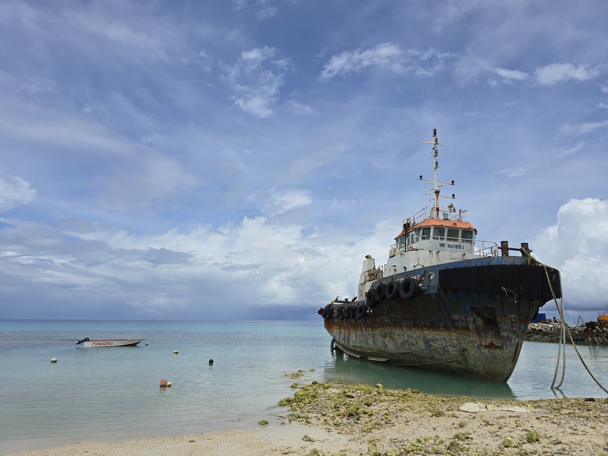 A rusting tugboat beached on the lagoon shore