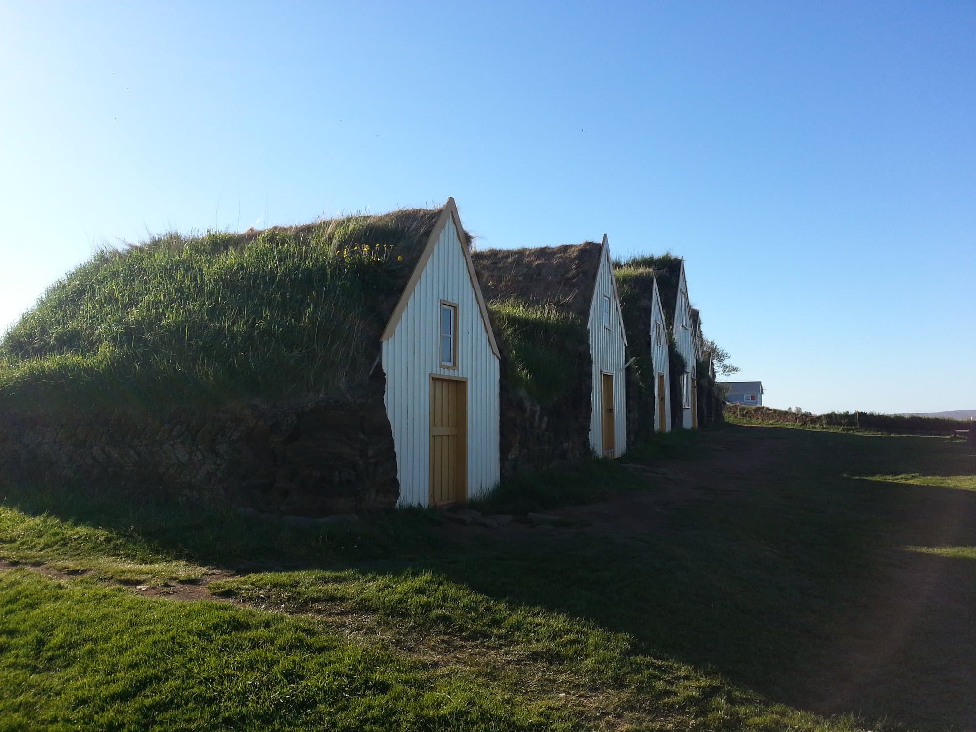 A row of grass-roofed turf houses set into a green bank