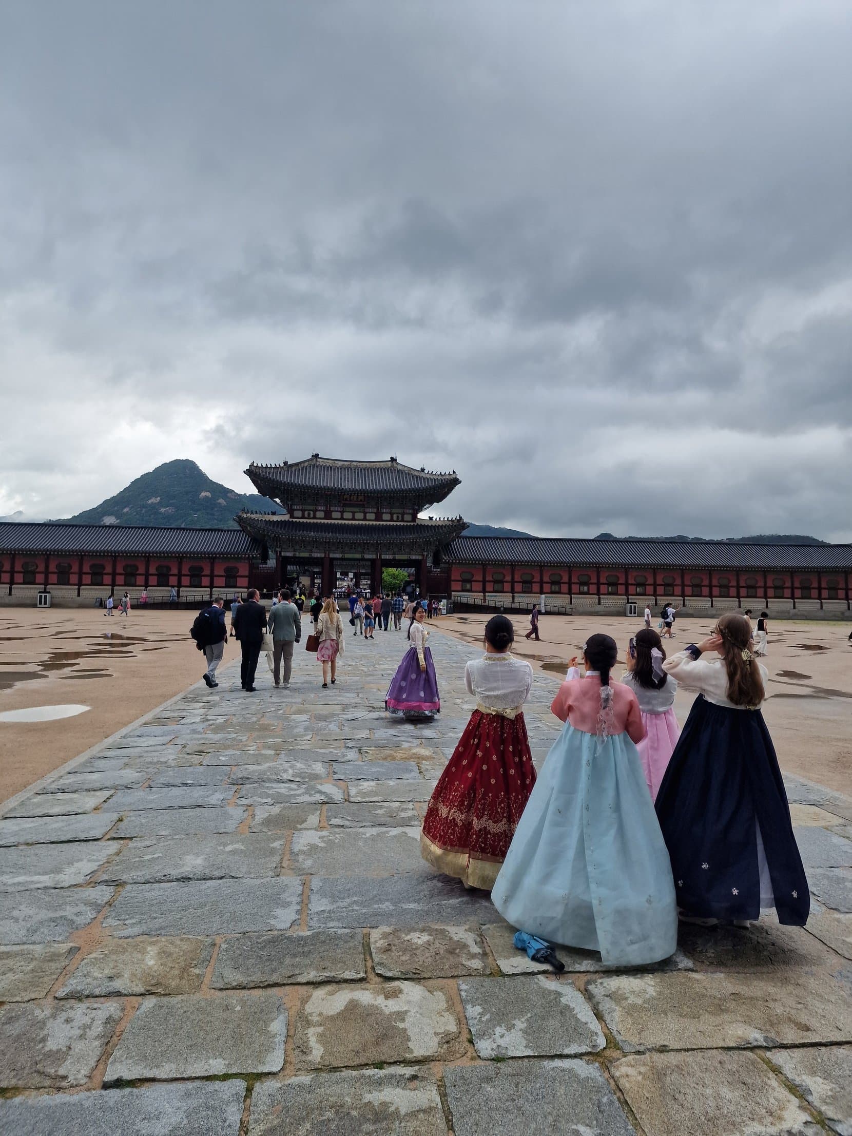 Two visitors in flowing hanbok walking toward Gwanghwamun gate at Gyeongbokgung, Seoul