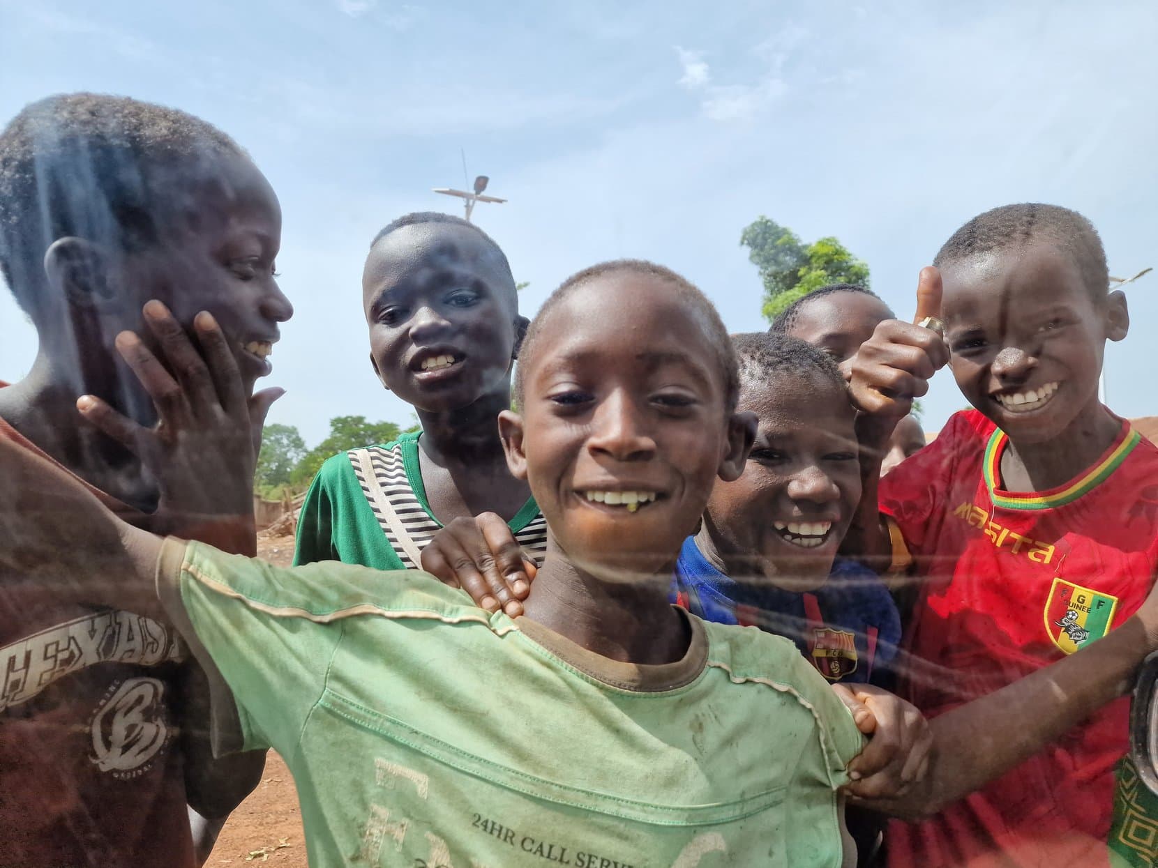 Village children smiling and crowding towards the camera, Guinea