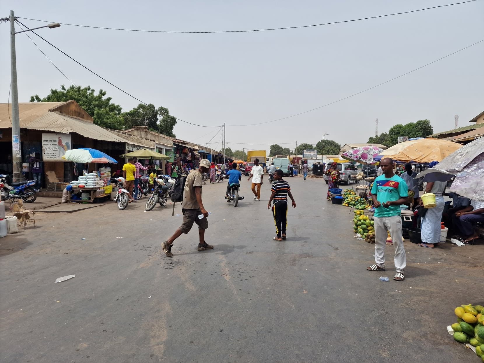 A village street market beside the road in southern Senegal, stalls and traffic
