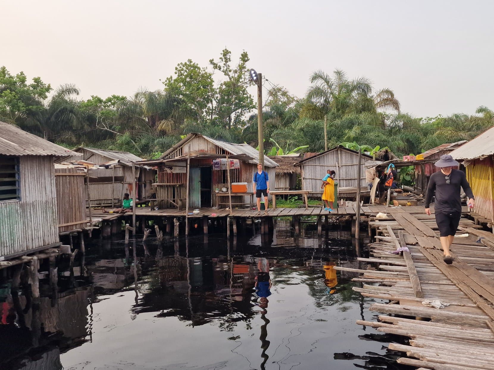 A woman walking the boardwalk between stilt houses and moored dugouts, Nzulezo, Ghana