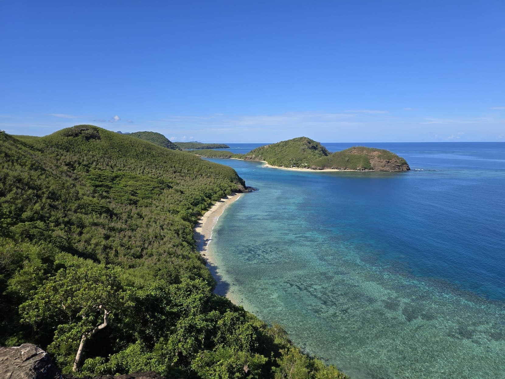 Looking down a green Yasawa island ridge to turquoise reef water and an offshore islet